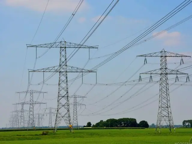 Hoogspanningsleidingen door een mooi weiland. Aanleg van hoogspanningsmasten bedreigt de natuur.